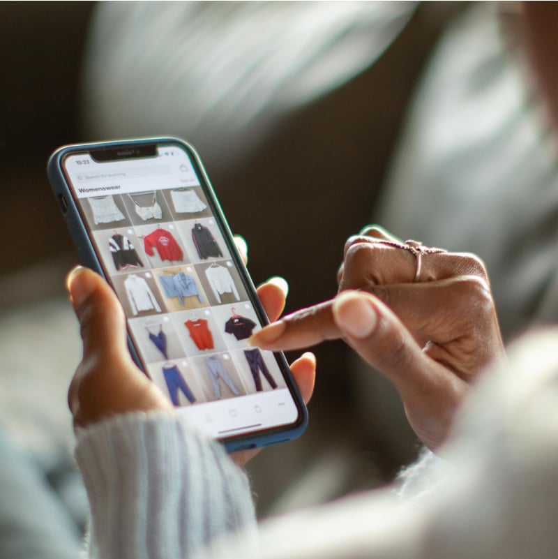A consumer browses an array of clothing choices on their mobile device