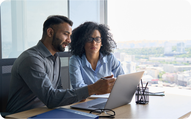 A pair of colleages analyze business insights from a computer in an office setting